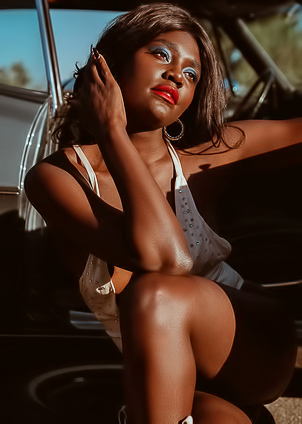 Victoria Antoinette Poses Topless In White Bodysuit Beside Vintage Car Under Blue Sky Hills